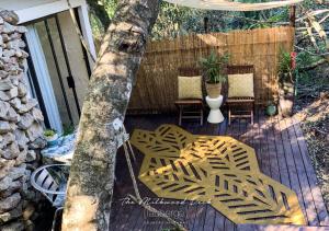 una terrazza in legno con tavolo, sedie e un albero di L'auberge Country Hideaway a Port Elizabeth