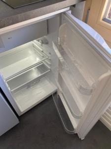 an empty refrigerator with its door open in a kitchen at Studio Lac Noir in Chandolin