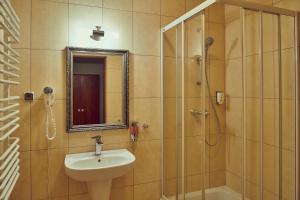 a bathroom with a sink and a shower with a mirror at Zajazd Srebrna Gora in Kraków