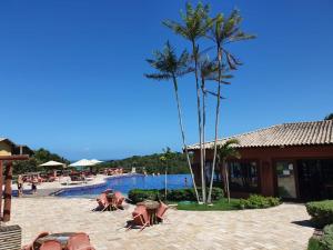 ein Resort-Schwimmbad mit Menschen, die auf dem Boden liegen in der Unterkunft Bangalô Villas do Pratagy in Maceió
