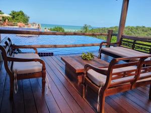 eine Terrasse mit 2 Stühlen, einem Tisch und einem Pool in der Unterkunft Bangalô Villas do Pratagy in Maceió