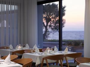 a dining room with tables and chairs with a view of the ocean at Cactus Hotel in Rhodes Town