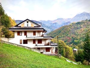 a house on a hill with mountains in the background at La Sorgente - Immersi nella natura in Limone Piemonte