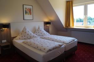 ein Schlafzimmer mit einem Bett mit Kissen darauf in der Unterkunft Hotel Neuses in Cuxhaven