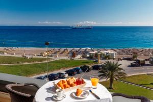 a table with a plate of food on a balcony with the ocean at Cactus Hotel in Rhodes Town