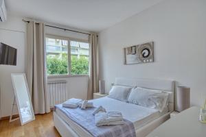 a white bedroom with a bed and a window at Horizon Suites in Cefalù