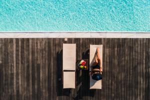 una mujer en bikini al borde de una piscina en Black Rose Beach Suites, en Perivolos
