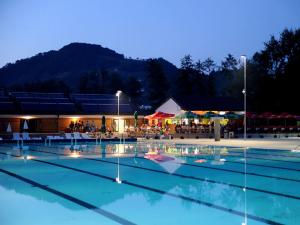 a large swimming pool at night with a group of tables at Country House Budana in Brestanica