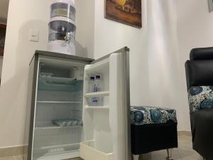 an empty refrigerator with its door open next to a chair at Hermoso apartamento con parqueadero in Fusagasuga