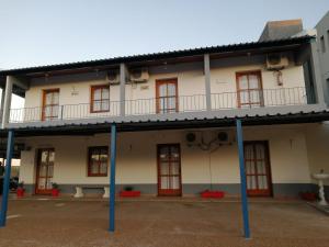 Edificio antiguo con ventanas rojas y balcón en POSADA SANTA CECILIA, en Termas del Daymán