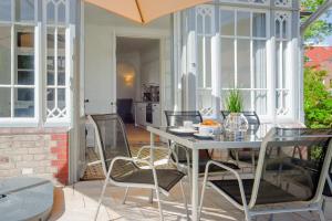 une terrasse avec une table, des chaises et un parasol dans l'établissement Gutshaus No2, à Heiligenhafen