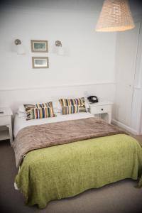 a bedroom with a bed with a green blanket and pillows at Beachlands Hotel in Weston-super-Mare