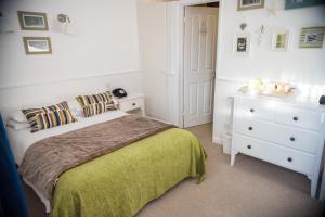 a white bedroom with a bed and a dresser at Beachlands Hotel in Weston-super-Mare