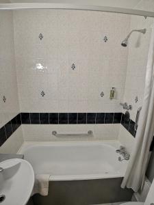 een badkamer met een wit bad en een wastafel bij Lancaster Hall Hotel in Londen