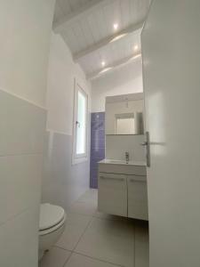 a white bathroom with a toilet and a sink at villetta sul mare Rachele in Marina di Campo