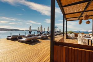 a deck with chairs and umbrellas on the water at Kaya Palazzo Resort & Residences Le Chic Bodrum in Bodrum City