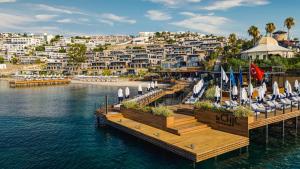 a dock with chairs and umbrellas on the water at Kaya Palazzo Resort & Residences Le Chic Bodrum in Bodrum City