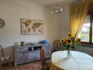 une salle à manger avec une table et un vase de tournesols dans l'établissement Maison Claudette, à Ronchi