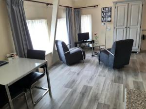 a living room with chairs and a table and a computer at Logement 'De witte klok' in Oude Bildtzijl