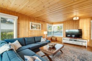 a living room with a blue couch and a tv at Madrona Beach House in Madrona Beach