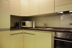 una cucina con lavandino e forno a microonde di Apartment Enzian mit Mitbenutzung SPA & Wellness - GRIWA RENT AG a Beatenberg