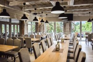 a restaurant with wooden tables and chairs and windows at Csikar Csárda és Panzió in Kőszeg