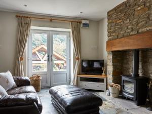 a living room with a couch and a stone fireplace at Lilly Cottage in Lydney
