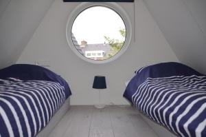 two beds in a room with a round window at Froukje's B&B in Woerdense Verlaat