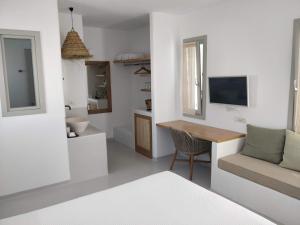 a white room with a bed and a desk and a television at Psathaki in Kimolos