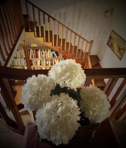 un vaso pieno di fiori bianchi di fronte a una scala di Book and Bed a Orvieto