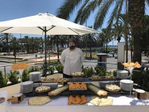 un hombre parado frente a una mesa con comida en Ohtels Gran Hotel Almeria, en Almería