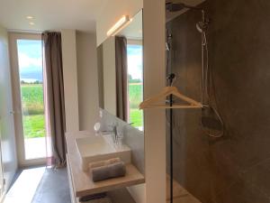 een badkamer met een wastafel en een douche met een glazen deur bij In 't Groen in Watou