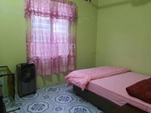a bedroom with a bed and a window with pink curtains at Homestay Bonda in Kampong Amir