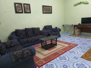 a living room with blue couches and a table at Homestay Bonda in Kampong Amir