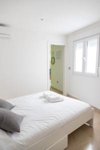 - un lit blanc dans une chambre blanche dotée d'une fenêtre dans l'établissement Apartamento Colon by Cadiz Time, à Cadix