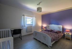 a bedroom with a white bed and a purple wall at GITE DU MORS-DORE in Le Sapt