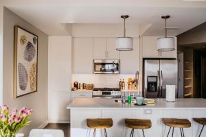 a kitchen with white cabinets and a counter with bar stools at Kasa The Gulch Nashville in Nashville