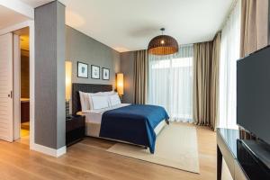 a bedroom with a bed and a flat screen tv at Kaya Palazzo Resort & Residences Le Chic Bodrum in Bodrum City