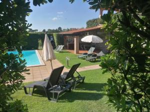 a backyard with a pool and two chairs and an umbrella at Le Vecchie Scuderie in Passo Corese