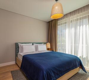 a bedroom with a blue bed and a window at Kaya Palazzo Resort & Residences Le Chic Bodrum in Bodrum City