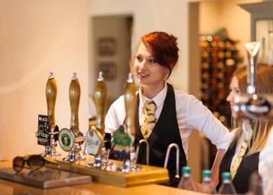 una mujer en un bar con botellas de cerveza en The Woodhouse Arms, en Grantham