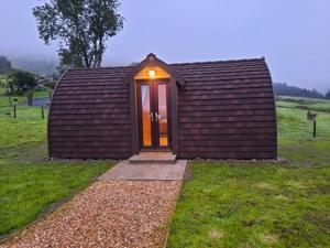 um pequeno barracão com uma porta num campo em Bwlcheinion Sea View Glamping em Machynlleth
