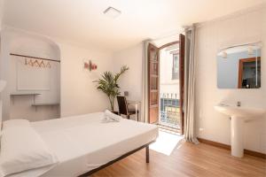 a white bedroom with a bed and a sink at Pensión Zacatin in Granada