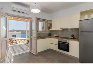 a kitchen with white cabinets and a view of the ocean at Pasithea Deluxe in Tripiti