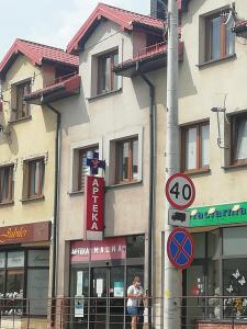 Un uomo è in piedi di fronte a un edificio di APARTAMENT W CENTRUM OLESNA a Olesno