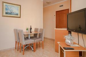 een woonkamer met een tafel en een televisie bij Apartments Posejdon in Utjeha