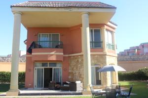 a house with a table and an umbrella in front of it at Stand alone Villa at Blumar North coast -SIDI ABD ALRAHMAN in El Alamein