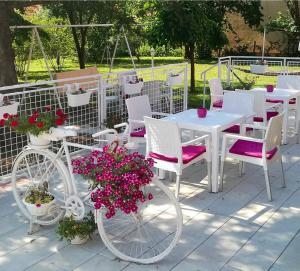a white table and chairs and a bike with flowers at Maslina Rooms in Smederevo