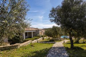 a stone path in a park with trees and a house at l'Albitru in Bonifacio