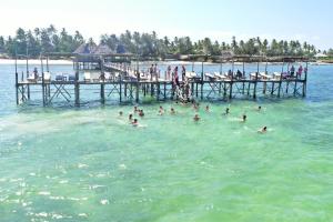 a group of people swimming in the water near a pier at Paradise Beach Resort & Spa in Uroa